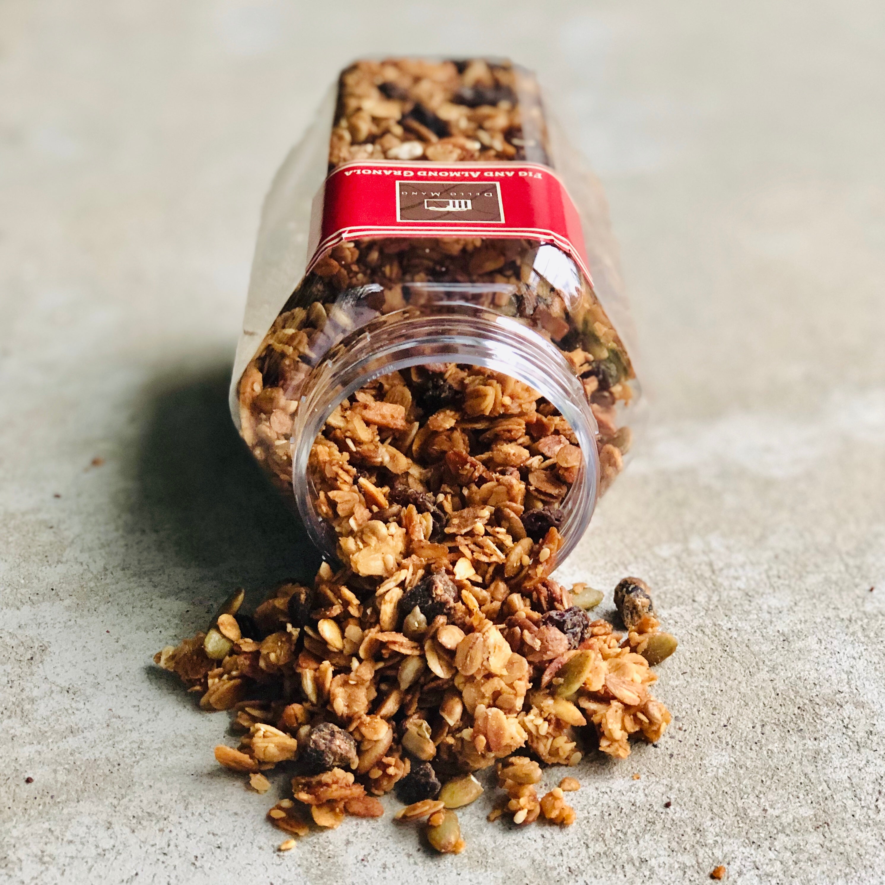 Fig and almond granola spilling from the jar onto concrete